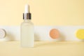 Anti-aging hyaluronic acid facial serum on pastel yellow background with neo-geometric conceptualism decor, front view. Mockup