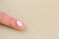 Anti anxiety white pill medicine on finger with blurred yellow b