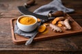 Anti-inflammatory food ingredient, turmeric powder in a ceramic bowl and fresh root on wooden background Royalty Free Stock Photo