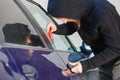 Thieft man holding screwdriver breaking into car