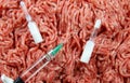 Antibiotic use in food producing animals concept: two white ampules, syringe and injection needle with minced raw meat background Royalty Free Stock Photo