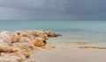 Antigua beach and rock jetty with gentle waves and storm clouds on calm sea Royalty Free Stock Photo