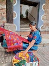 Cheerful mayan indian woman wearing a traditional huipil crafting handmade weavings in the city of Antigua in Guatemala. Royalty Free Stock Photo