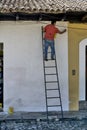 Antigua, Guatemala: painter paints a wall on a ladder