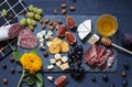 Antipasti food dark blue flat lay with nuts, honey, cured meat, salami, cheeses, grapes and figs.