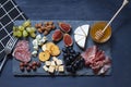 Antipasti food dark blue flat lay with nuts, honey, cured meat, salami, cheeses, grapes and figs.