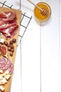 Antipasti food white flat lay with nuts, honey, cured meat, salami, cheeses, grapes and figs.