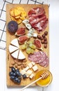 Antipasti food white flat lay with nuts, honey, cured meat, salami, cheeses, grapes and figs on the wooden board.