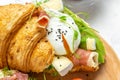 Antipasti snacks croissant sandwich with prosciutto, poached egg, jamon, blue, cheese, avocado, microgin and cherry tomatoes on a