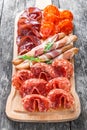 Antipasto platter cold meat plate with grissini bread sticks, prosciutto, slices ham, beef jerky, salami and arugula on board Royalty Free Stock Photo