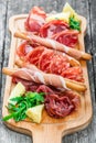 Antipasto platter cold meat plate with grissini bread sticks, prosciutto, slices ham, beef jerky, salami on cutting board Royalty Free Stock Photo