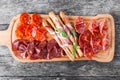 Antipasto platter cold meat plate with grissini bread sticks, prosciutto, slices ham, beef jerky, salami on cutting board Royalty Free Stock Photo