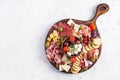 Antipasto platter with ham, prosciutto, salami, cheese, crackers and olives on a light background.