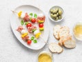 Antipasto skewers. Mediterranean appetizer to wine - prosciutto, bell peppers, cherry tomatoes, mozzarella cheese on skewers and w Royalty Free Stock Photo