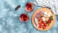 Antipasto sliced Spanish Fuet salami wurst, Camembert cheese, strawberries and glass rose wine on blue background. banner, menu Royalty Free Stock Photo