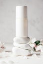 Antiperspirant roll-on deodorant on stack of white pebble stones, on light plaster surface with apple flowers Royalty Free Stock Photo