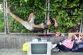 Man takes a break from selling used home appliance and naps on a string hammock at a sidewalk