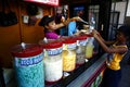 A woman sells assorted fruit juice and other refreshments during a hot summer day