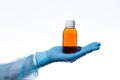 Antipyretic or cough syrup in a medical brown glass bottle with a white cap in a doctor\`s hand on a white background isolate