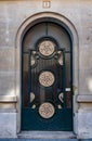 Antique arch door with mosaic rosettes and stone block wall of old building in Paris France. Vintage metal and matte glass doorway Royalty Free Stock Photo