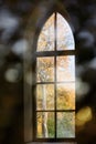 Antique arched window with view to autumnal landscape, bright sunshine.View through the window in autumn