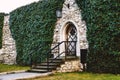 Antique arched wrought-iron doors in an old stone fortress wall using green lush ivy. Beautiful antique frnar over the old door Royalty Free Stock Photo