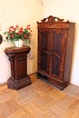 Antique beautiful wardrobe and a bouquet of flowers in a white vase on a wooden cabinet