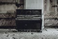 An antique black piano stands in an abandoned manor house.