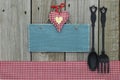 Antique blank blue sign with heart, gingham tablecloth and cast iron spoon and fork