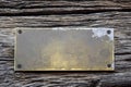 Antique blank brass rectangular plaque screwed with rusty screws to an old weathered board with deep wrinkles. Place for text