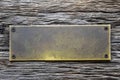 Antique blank brass rectangular plaque screwed with rusty screws to an old weathered board with deep wrinkles. Place for text Royalty Free Stock Photo