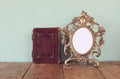 Antique blank victorian style frame and old book on wooden table. retro filtered image. template, ready to put photography