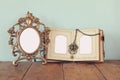 Antique blank victorian style frame and old open photograph album on wooden table. retro filtered image. Royalty Free Stock Photo