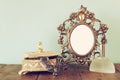 Antique blank victorian style frame, perfume bottle and neckless on wooden table. retro filtered image Royalty Free Stock Photo