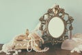 Antique blank victorian style frame, perfume bottle and white pearls on wooden table. retro filtered and toned Royalty Free Stock Photo