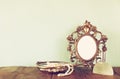 Antique blank victorian style frame, perfume bottle and white pearls on wooden table. retro filtered and toned Royalty Free Stock Photo