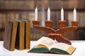 Antique books with an open book in front of an antique wooden candlestick on a bright table over abstract blurred library. Royalty Free Stock Photo