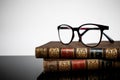 Antique books and reading glasses on a reflective surface. Daylight Royalty Free Stock Photo