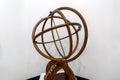 Antique brass armillary sphere on a wooden stand on white background. ancient scheme of the movement of celestial stars Royalty Free Stock Photo