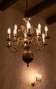 Antique brass chandelier with candle light bulbs hanging from roof or ceiling in a historic,midieval building and Royalty Free Stock Photo