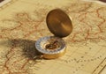 An antique brass compass rests open on a vintage map. The Royalty Free Stock Photo