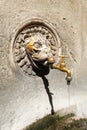 Antique brass drinking fountain in the shape of a lion, built into the wall of an old house