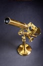 Antique brass microscope stands on a matt grey surface Royalty Free Stock Photo