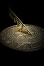 Antique brass sundial with time and calendar engraved on the surface.