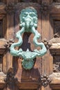 Antique bronze knocker decorating a carved wooden door Royalty Free Stock Photo