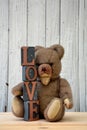 Antique brown teddy bear sitting with Love stones