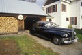 An antique car and stack of firewood in New England