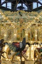 An antique carousel with an inticate ostrich carving below and mechanical systems visible overhead