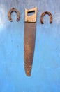Antique carpenter hand saw and two horseshoe on wall Royalty Free Stock Photo
