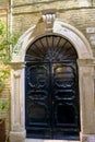 Antique carved black wooden door across the white arc in old town. Exterior facade. Royalty Free Stock Photo